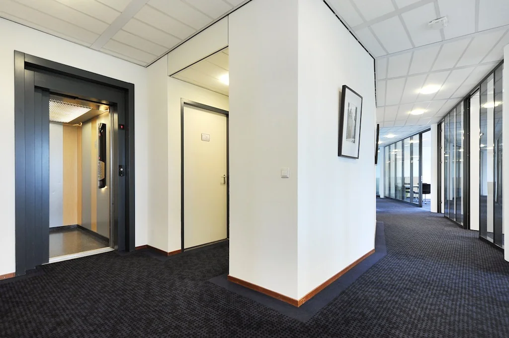 Moderne kantoorhal met lift, deuren en glazen wanden aan de Laan van ’s-Gravenmade.